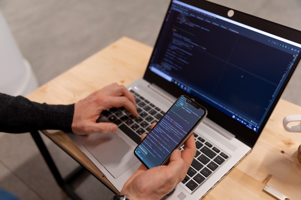 A programmer checking code on smartphone and lap top, testing