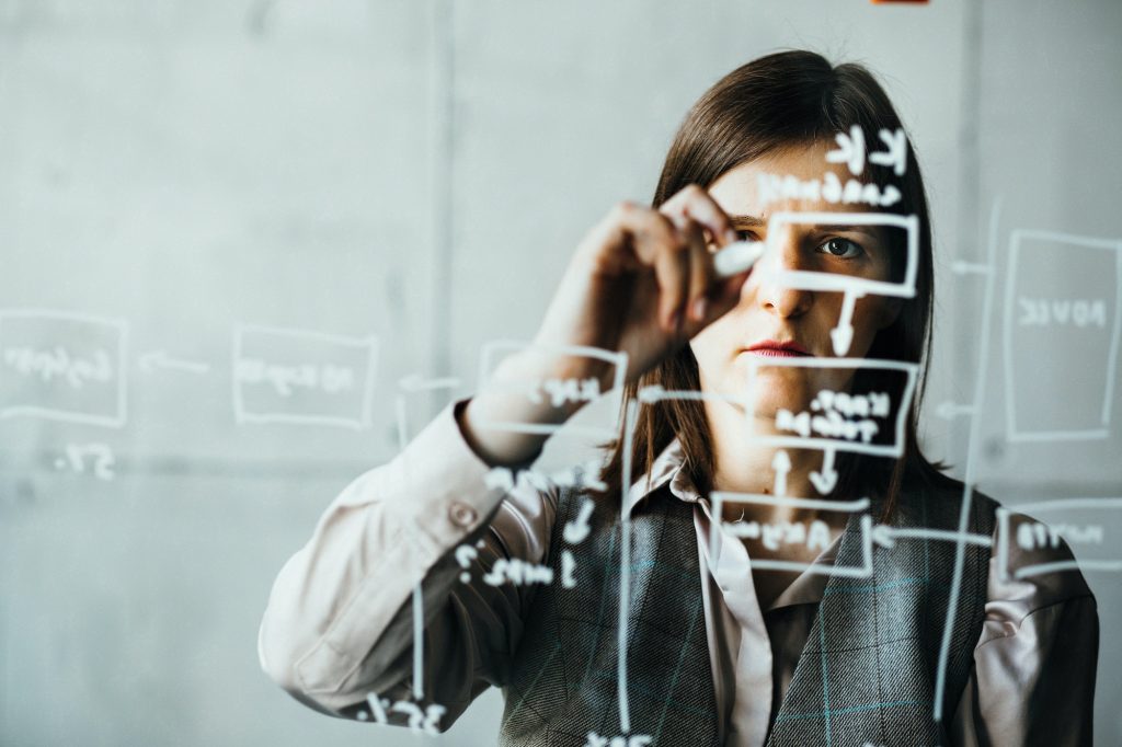 A woman writes with a white marker on a transparent board