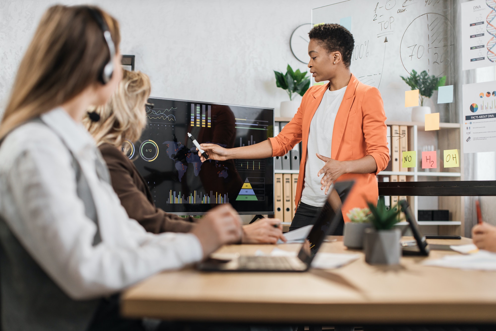 African american woman in orange suit showing financial statistic of enterprise during meeting