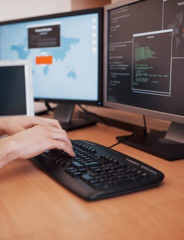 man uses a laptop computer with many monitors