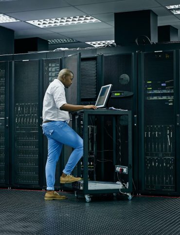 Skilled in all things IT. Shot of an IT technician using a computer while working in a data center.